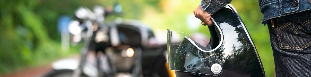 Rider walking towards motorcycle holding a helmet