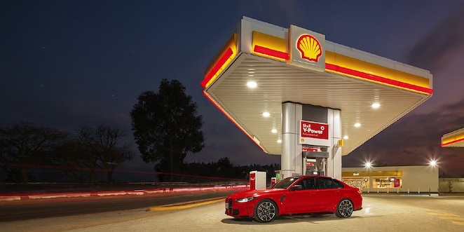 A red BWM M3 parked on a Shell Forecourt during dusk